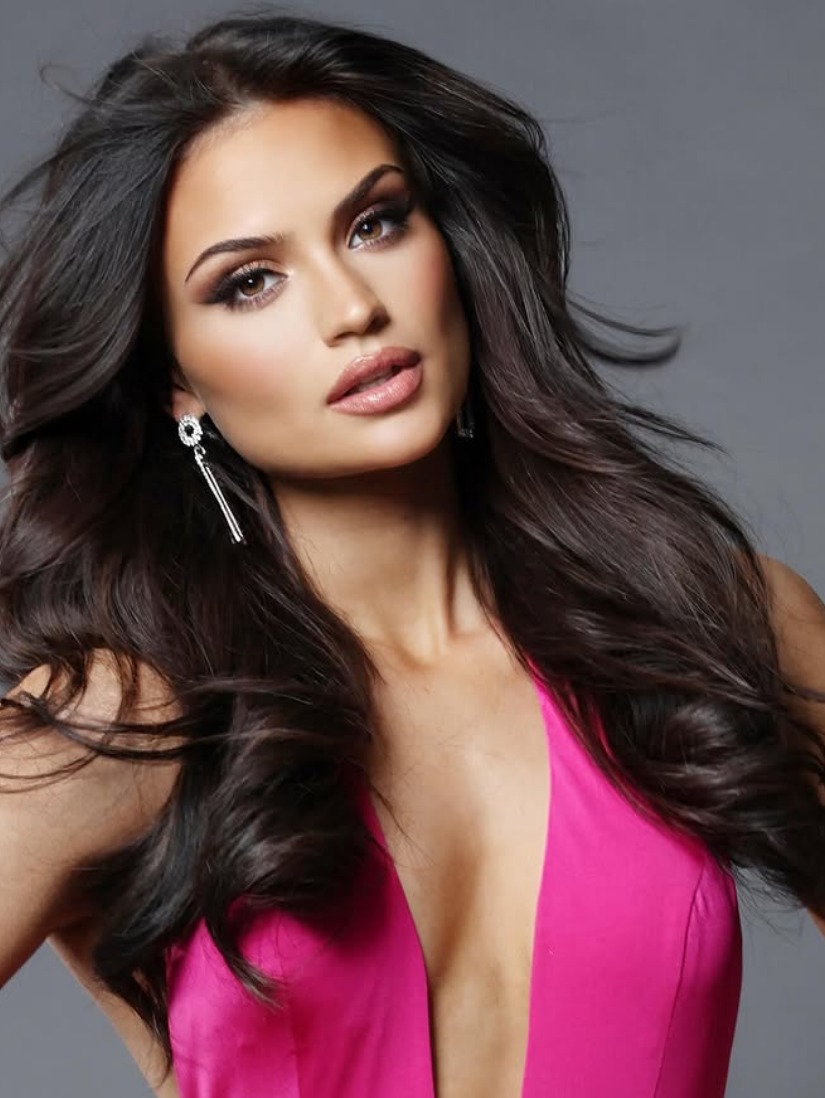 A studio portrait in a fuchsia gown with long silver drop earrings against a soft grey backdrop.
