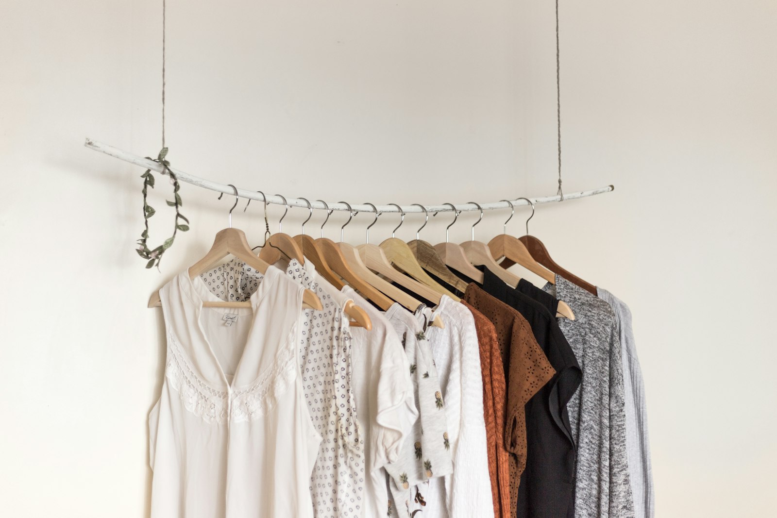 A neatly arranged wardrobe with a tailored blazer, a sheath dress on a wooden hanger, and a pair of nude pumps.